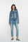 Geisha Fashion model wearing denim jacket and jeans, white background.
